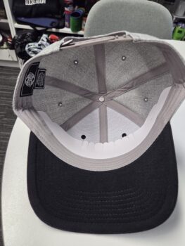 A gray and black cap viewed from the inside, resting on a white surface.