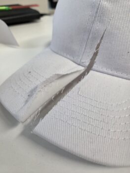 A white cap featuring a large, jagged cut across the brim and crown.