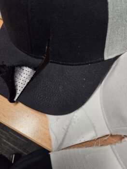 A black and white cap with a large cut through the front brim and crown.