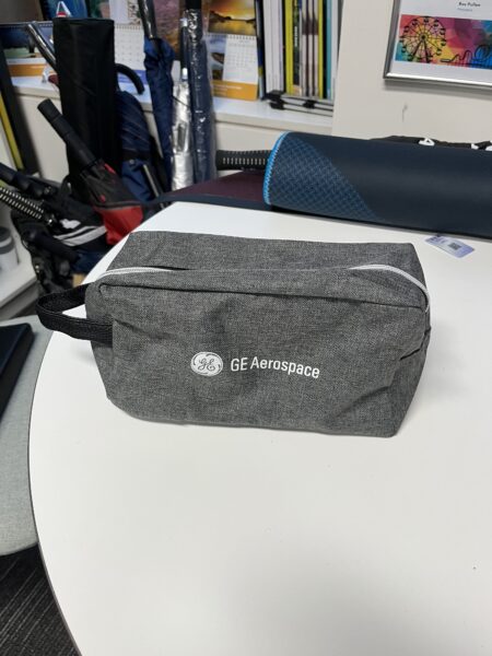 A gray GE Aerospace pouch rests on an office table with other items in the background.