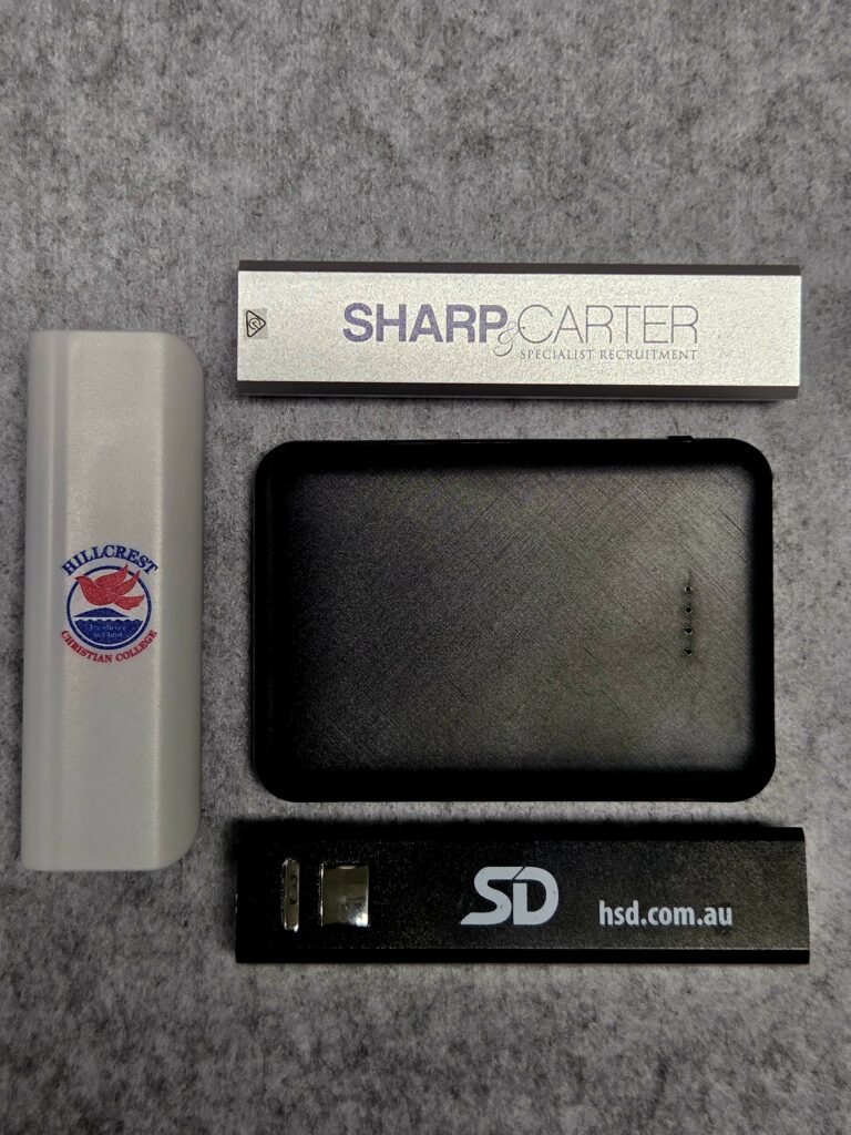 Four branded USB drives and a sleek power bank on a gray textured surface
