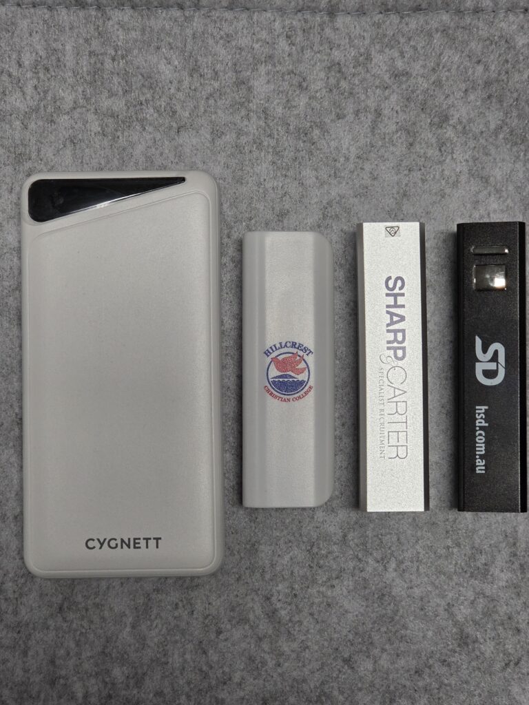 Four rectangular USB power banks on a gray surface, one labeled