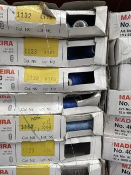 Boxes of blue and white embroidery thread spools stacked; Print Setup Fees may apply.