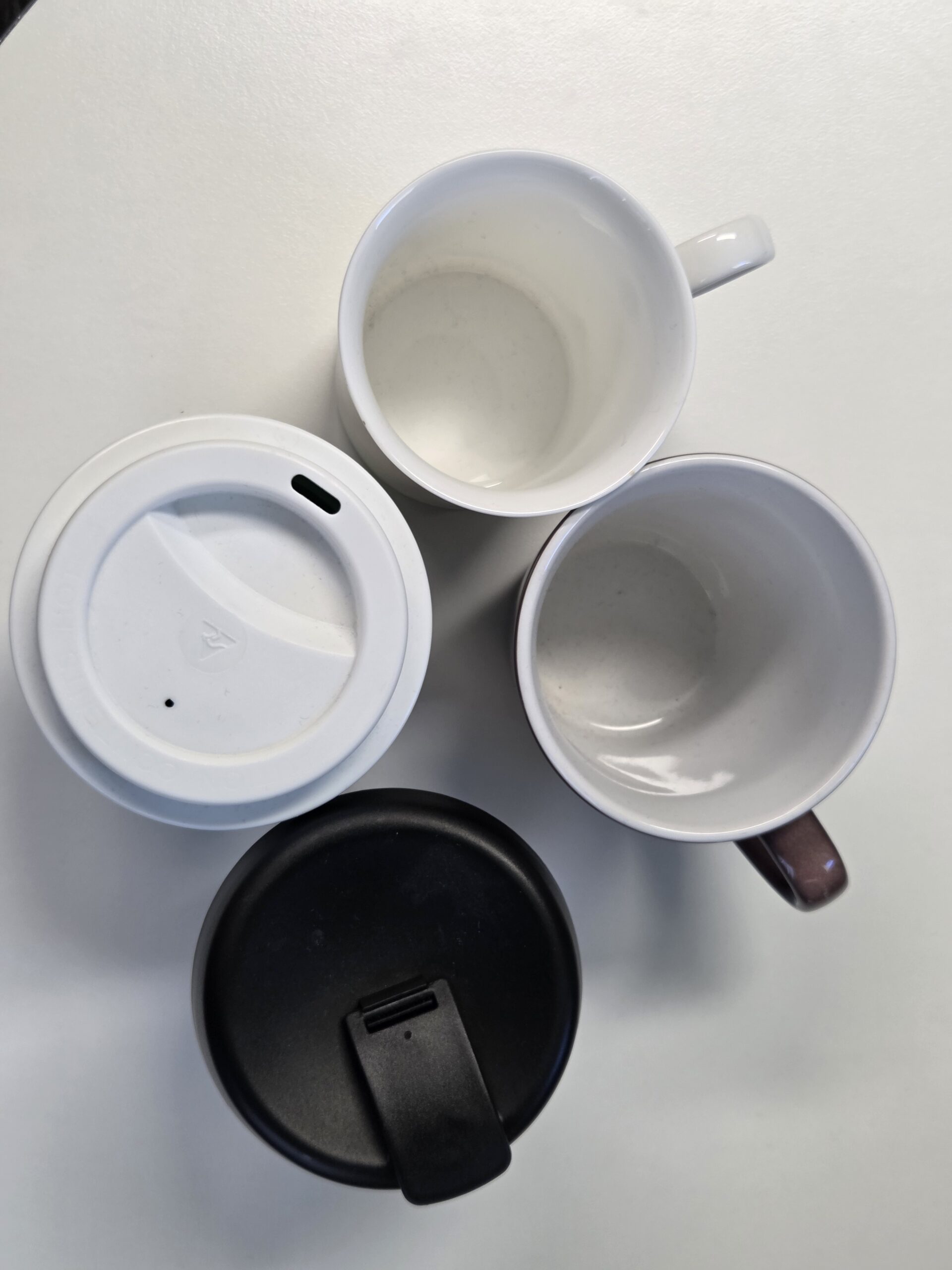 Two travel mugs with lids and two ceramic mugs—a promotional mugs guide from above.