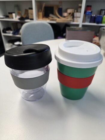 Two reusable cups with lids and bands, perfect as a promotional mugs guide in office settings.