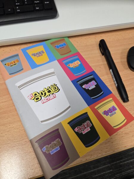 Notebook with colorful cup designs on a wooden desk, perfect for user generated content.