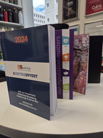 A 2024 RETIREINVEST planner stands on a table, a perfect buying guide for diaries seekers.