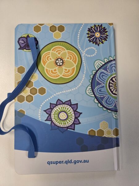 Blue mandala notebook with blue elastic band and qsuper branding on the cover.