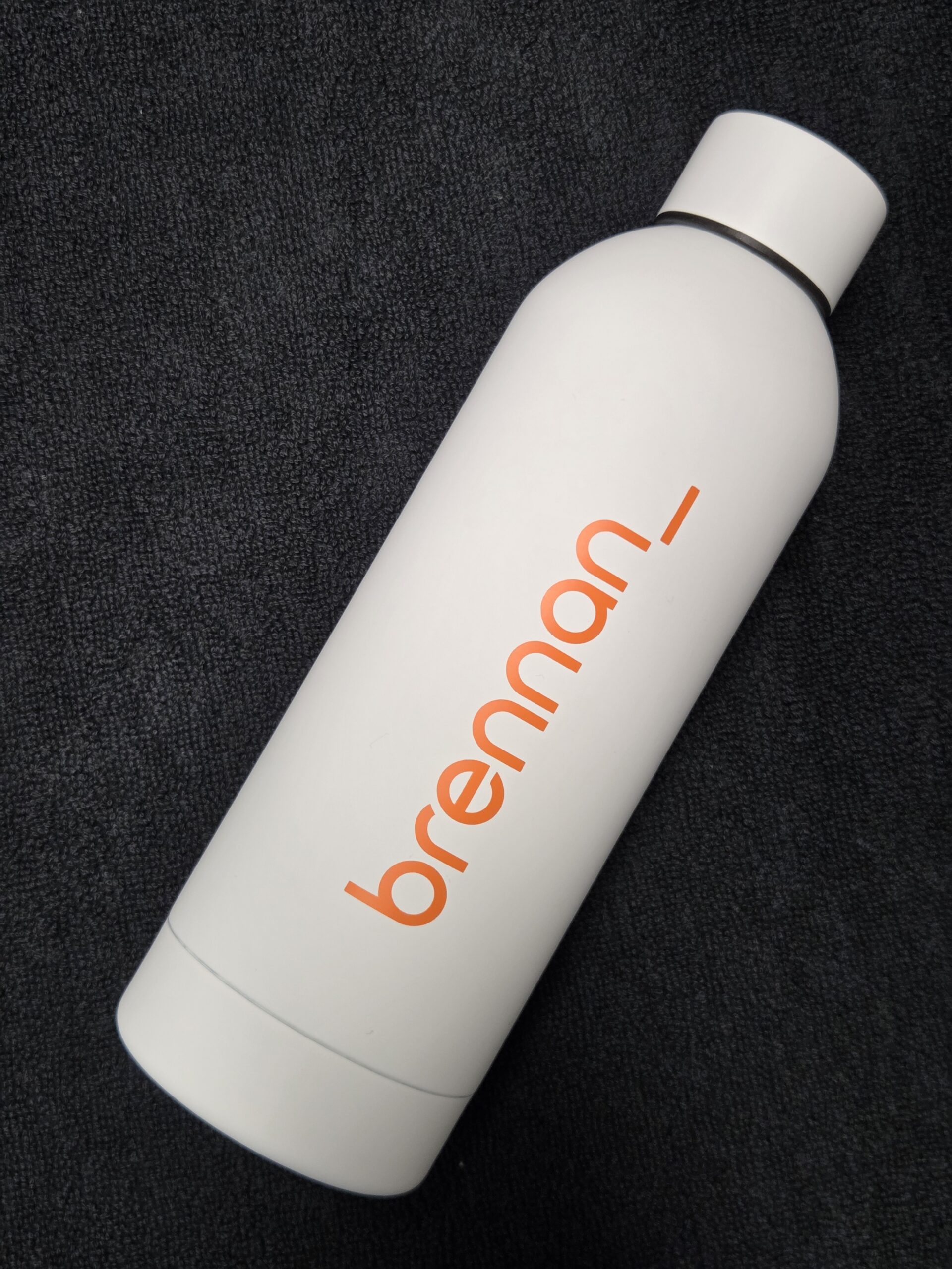 White which bottle on black background with brennan_ written in orange text.