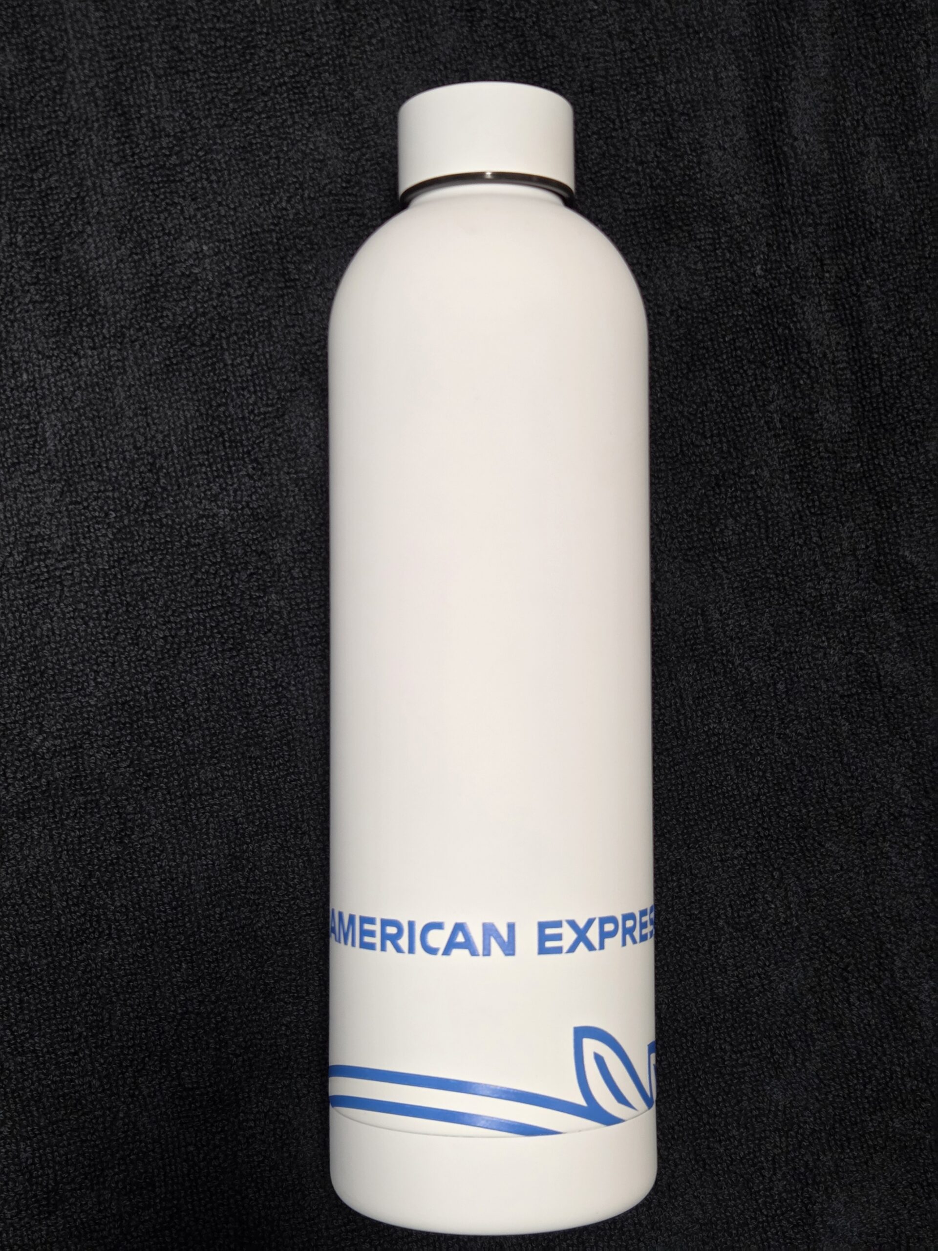 White American Express water bottle—guess which bottle stands out on this black textured surface.