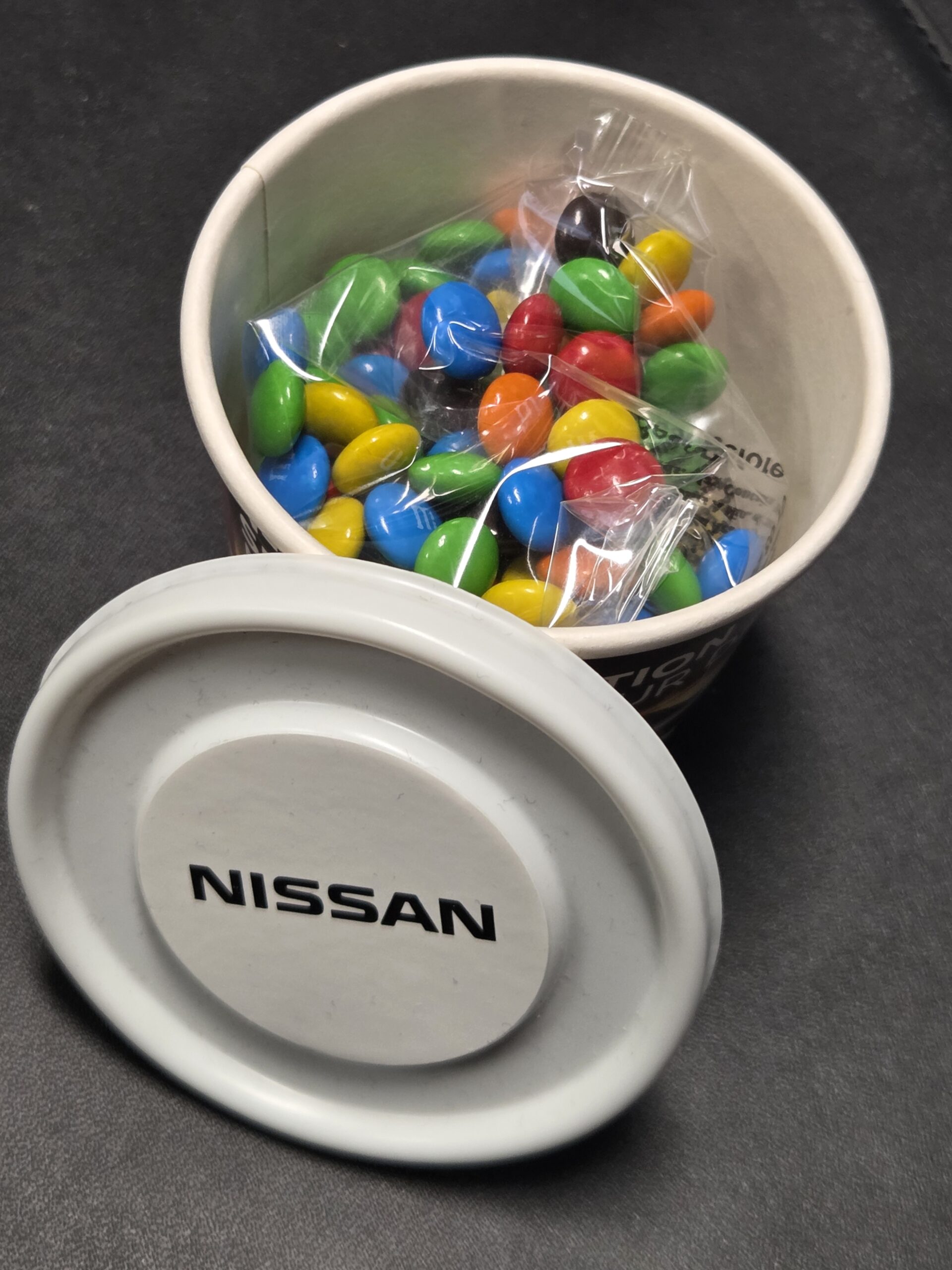 m&ms in a tub with white lid and nissan logo printed