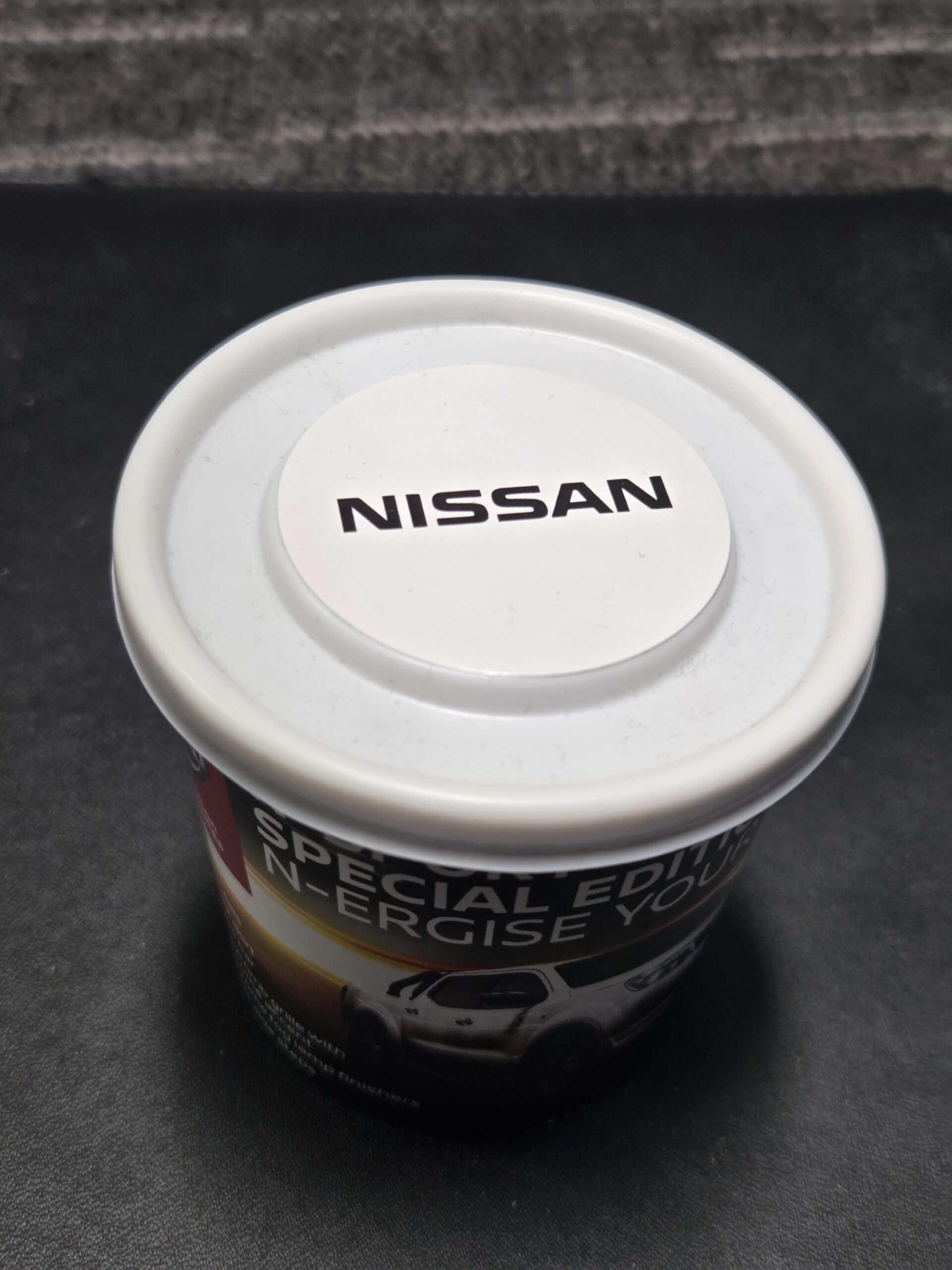 tub of m&ms with white lid and nissan logo