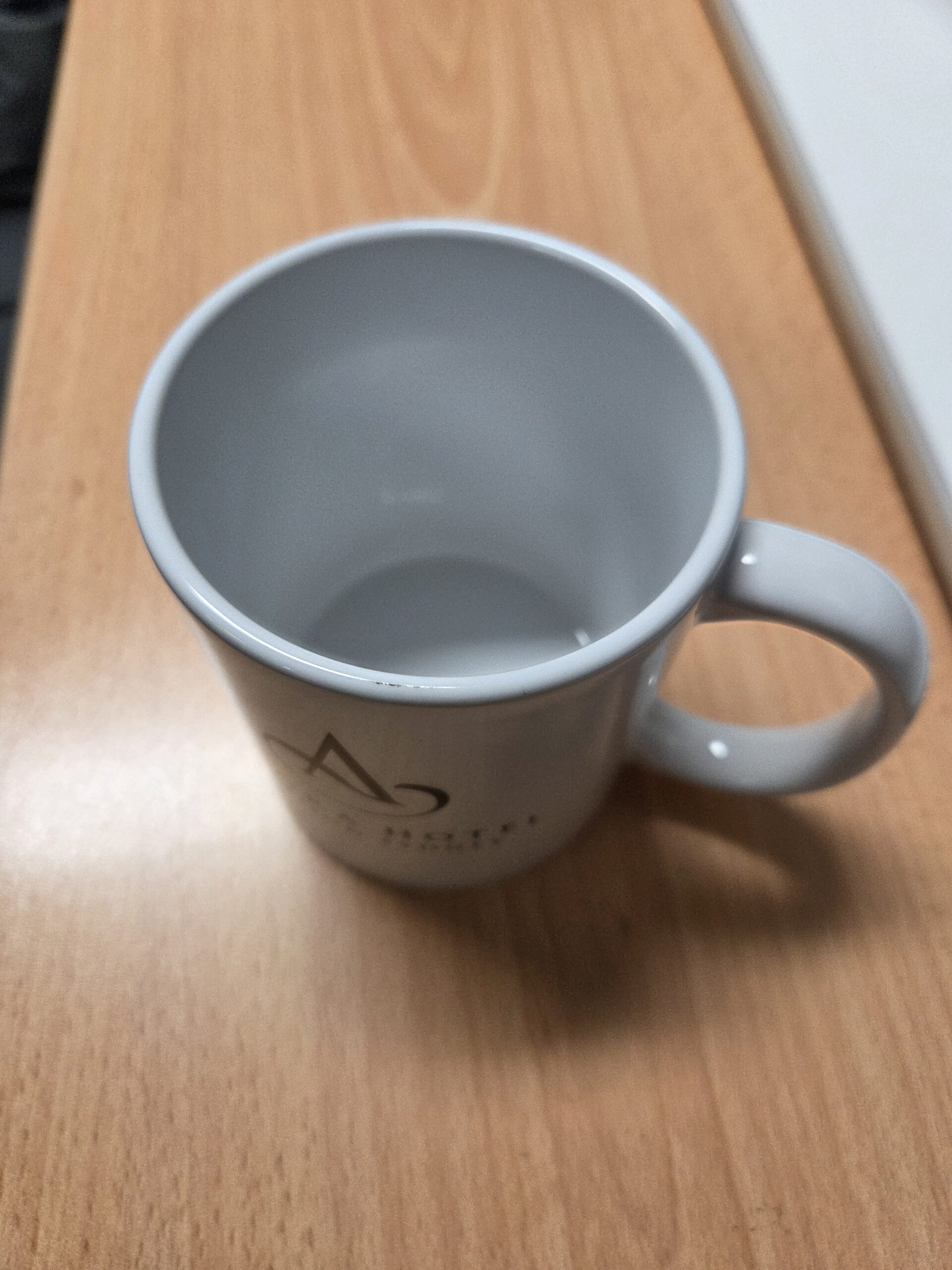 upper angle of the white mug on a wooden table