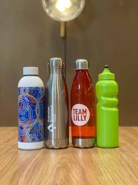 A set of water bottles in various colors and designs on a wooden surface, brown backdrop.