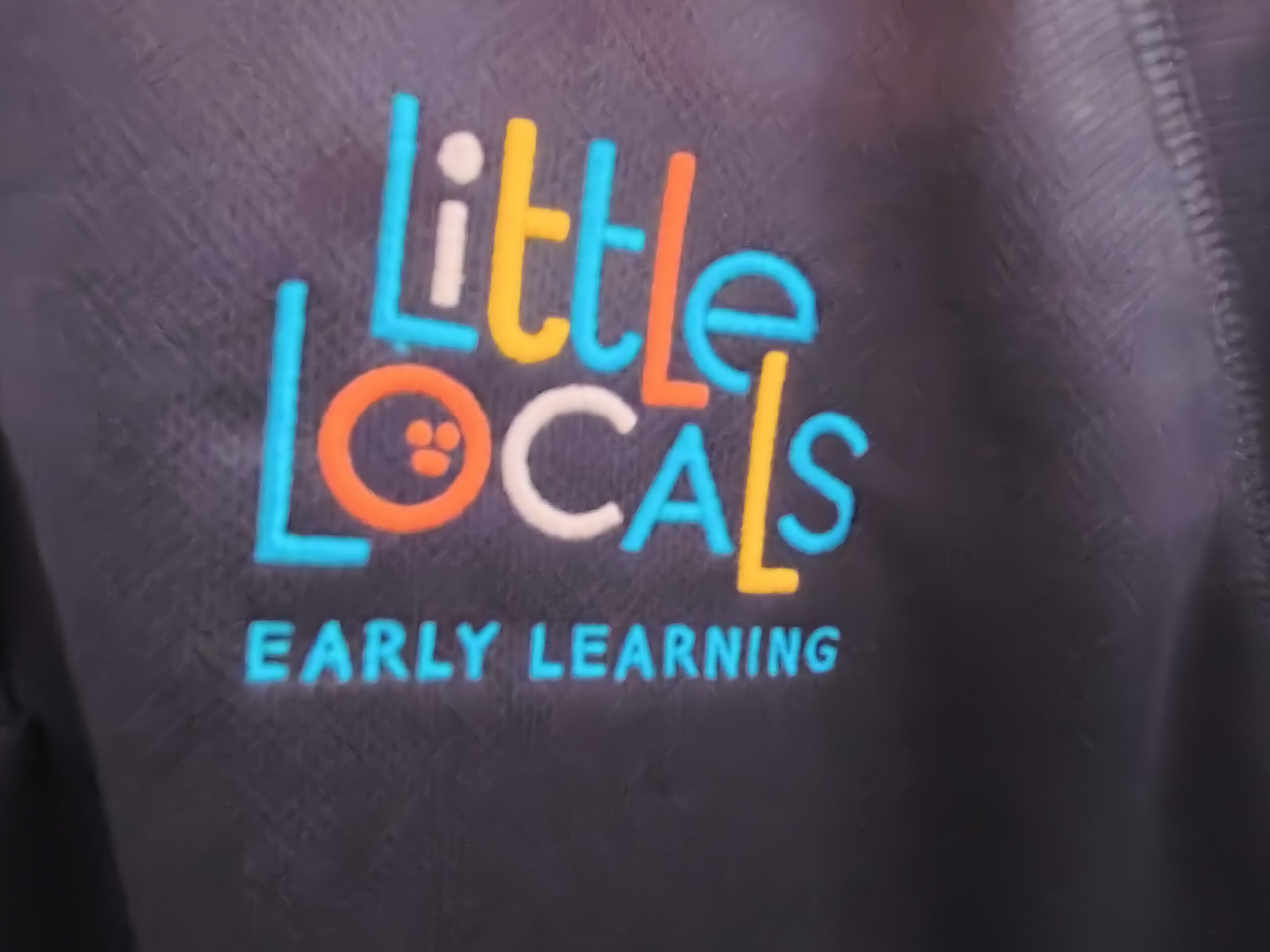 close up view of shirt with little locals early learning logo