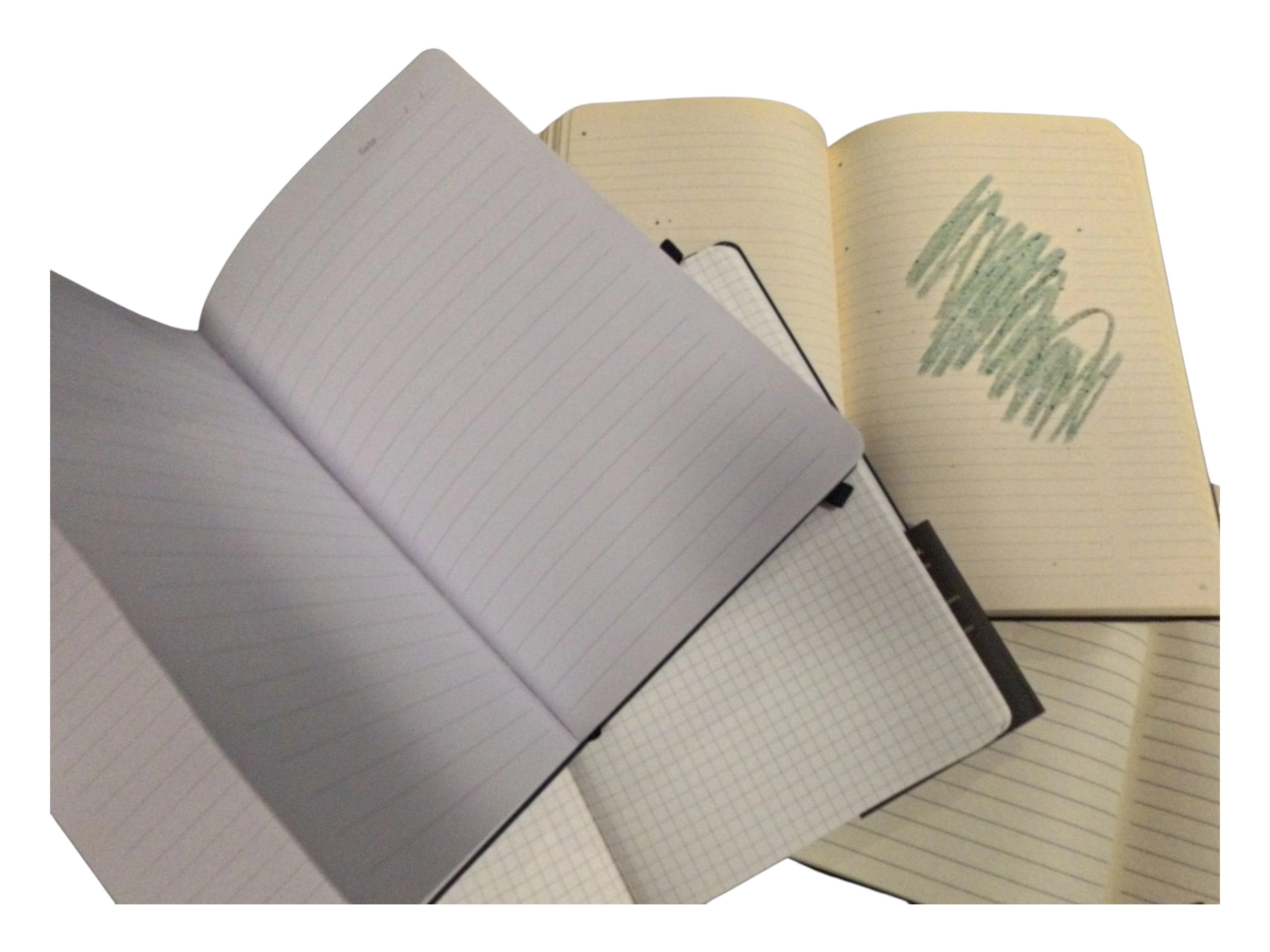 Four open notebooks—lined and grid pages—one features green scribbles.