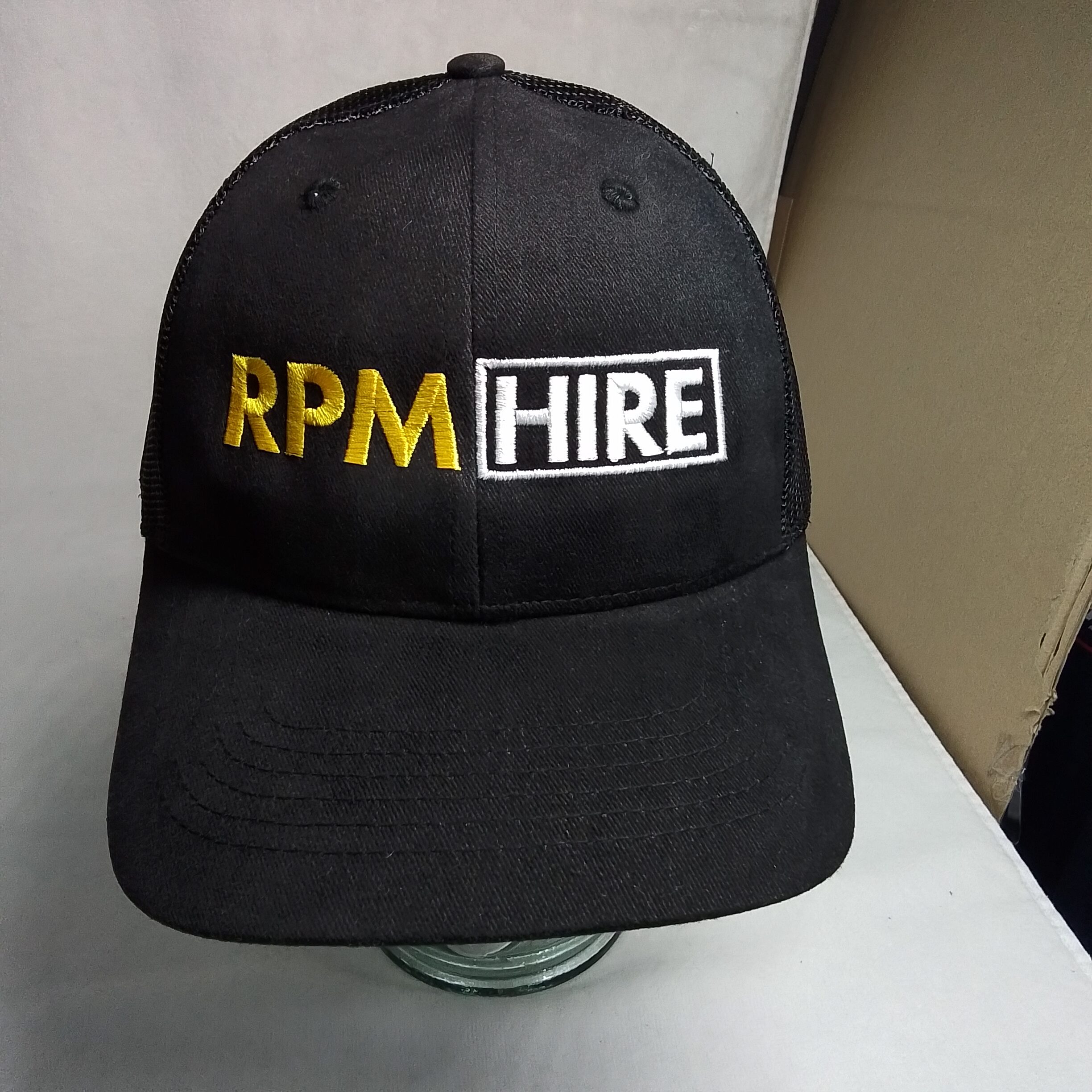 black cap embroidered with RPM Hire logo