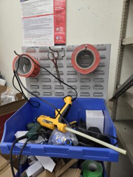 A blue bin with tools and tape rolls, perfect for organizing print setup fees in your workspace.