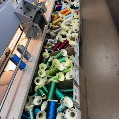 Spools of colorful thread organized in boxes, ready for use—no print setup fees required.