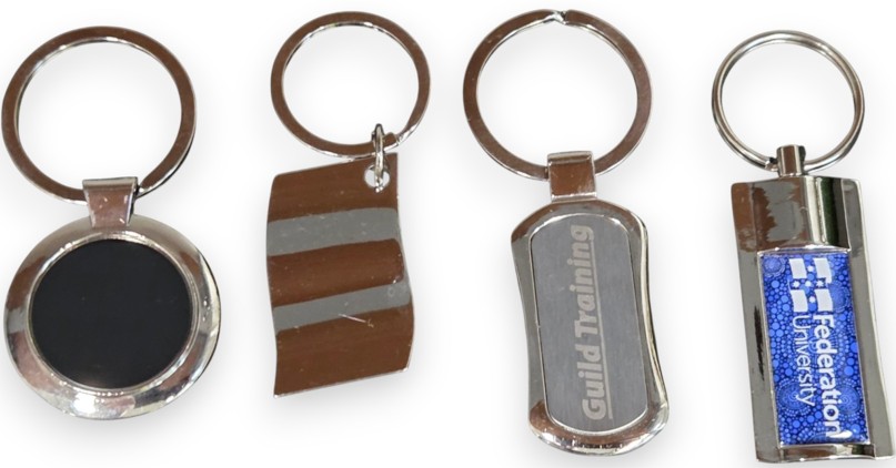 Four assorted metal vs plastic keyrings displayed in a row on a white background.