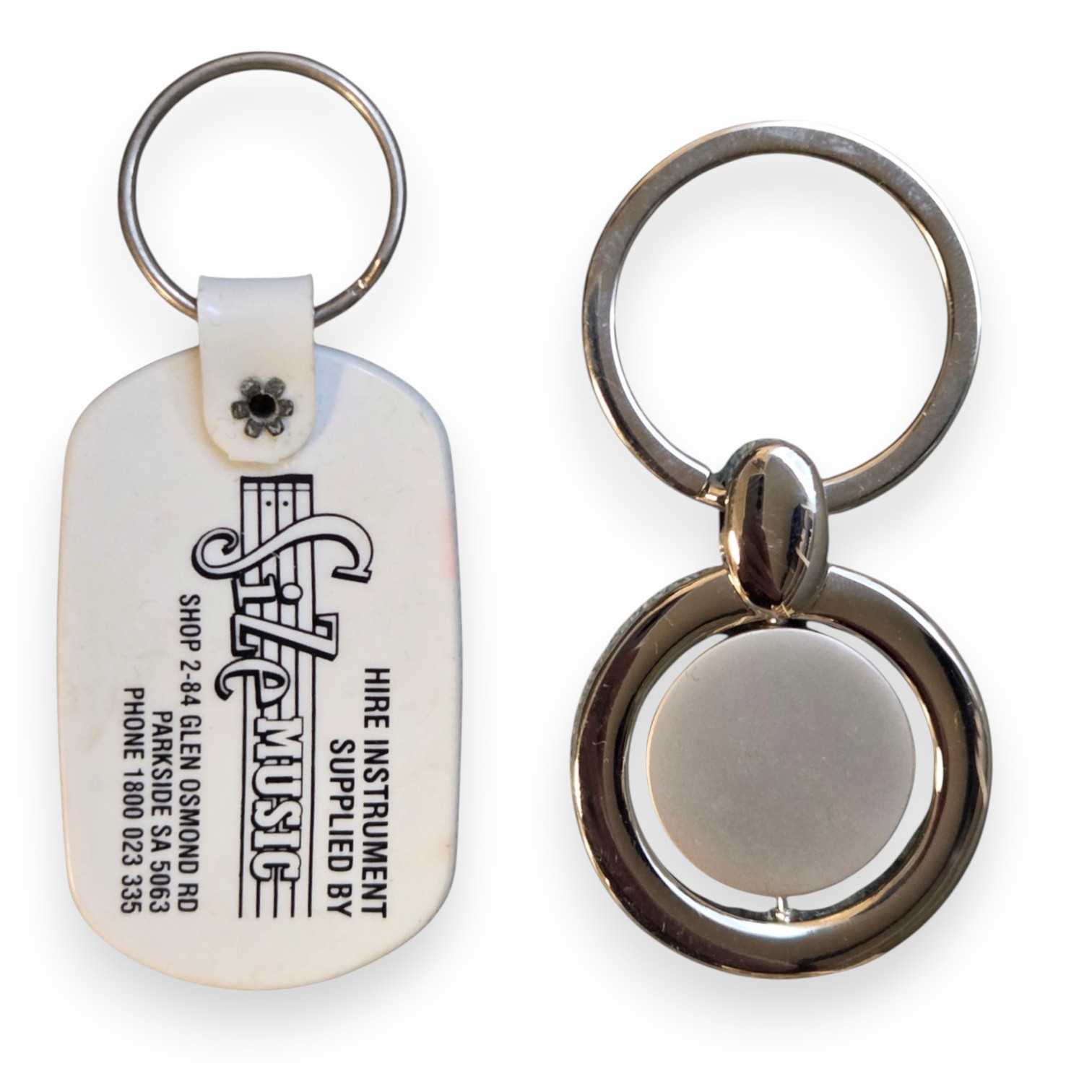 Two metal vs plastic keyrings; one with a white S.A. Music tag, the other plain and circular.