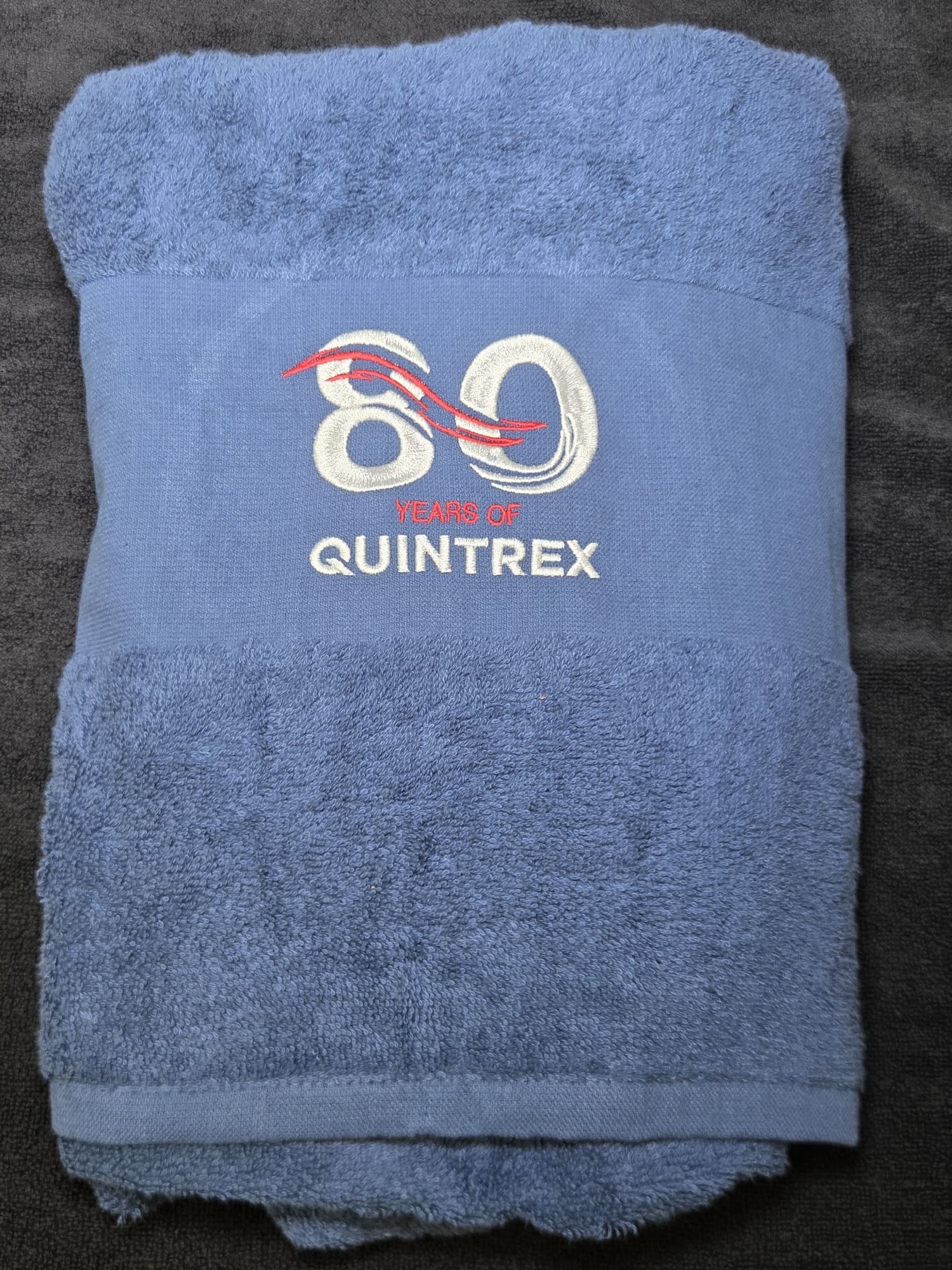 Blue towel featuring Quintrex 80 Years embroidery in white and red on the band.
