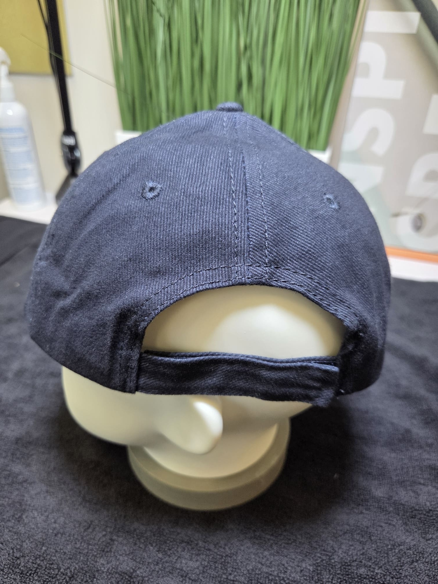 A navy blue ETC cap on a mannequin head, shown from the back, on a black cloth surface.