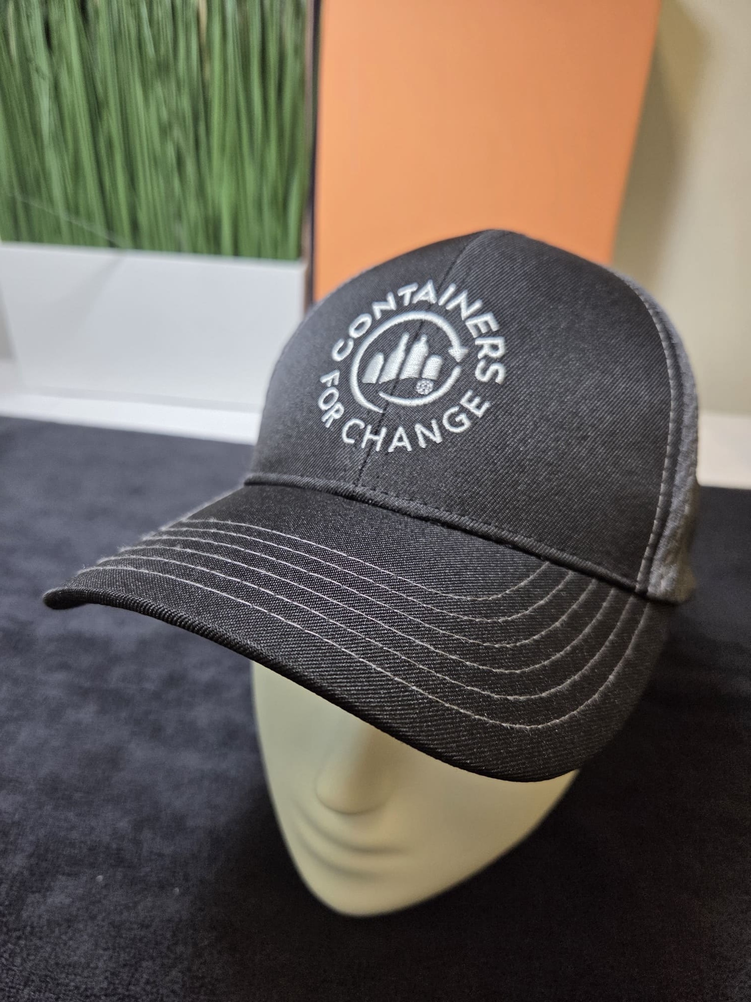 Containers for Change cap displayed on a mannequin head against a dark background.