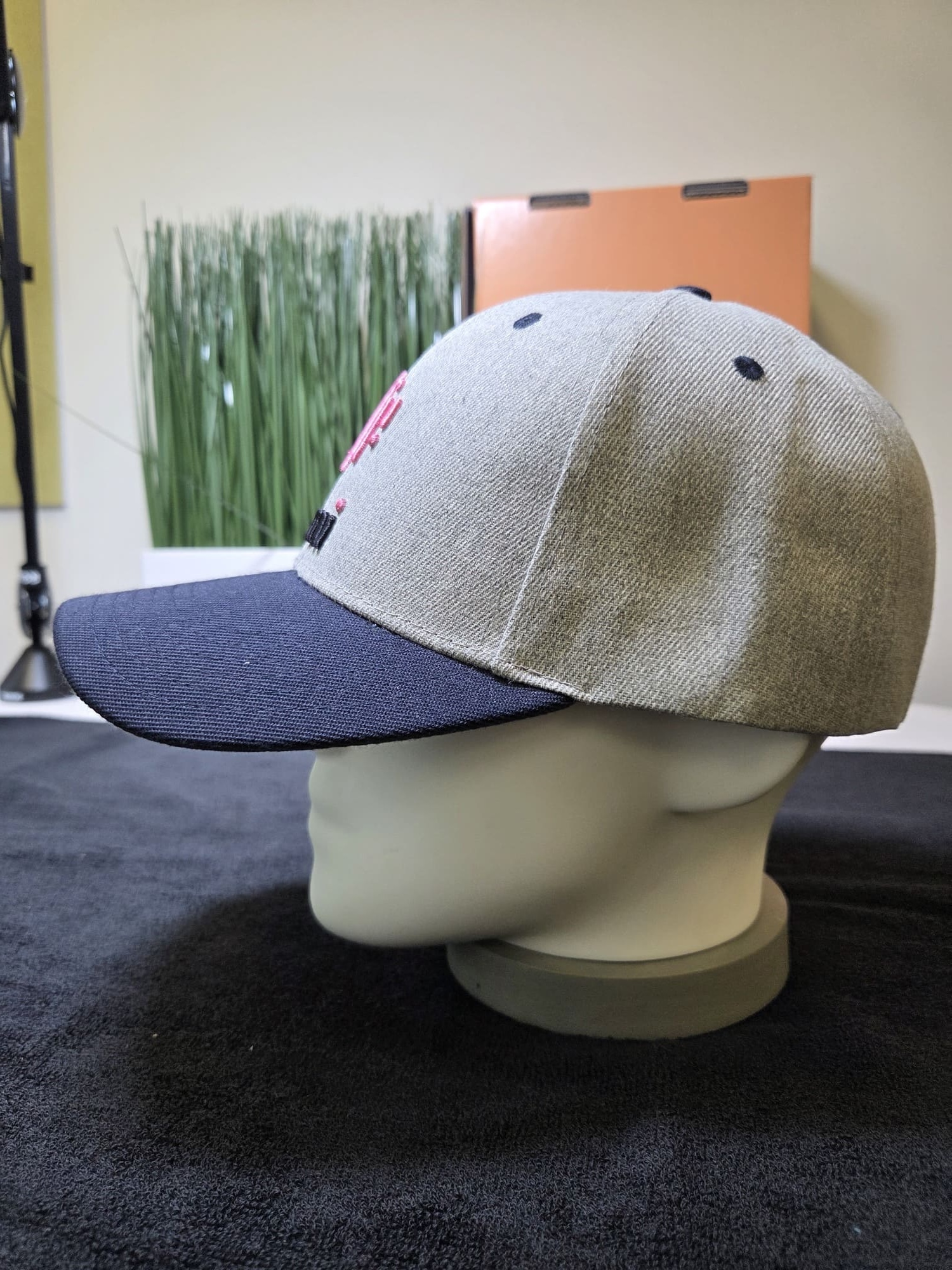 Gray and navy Lumi baseball cap displayed on a mannequin head, side view.