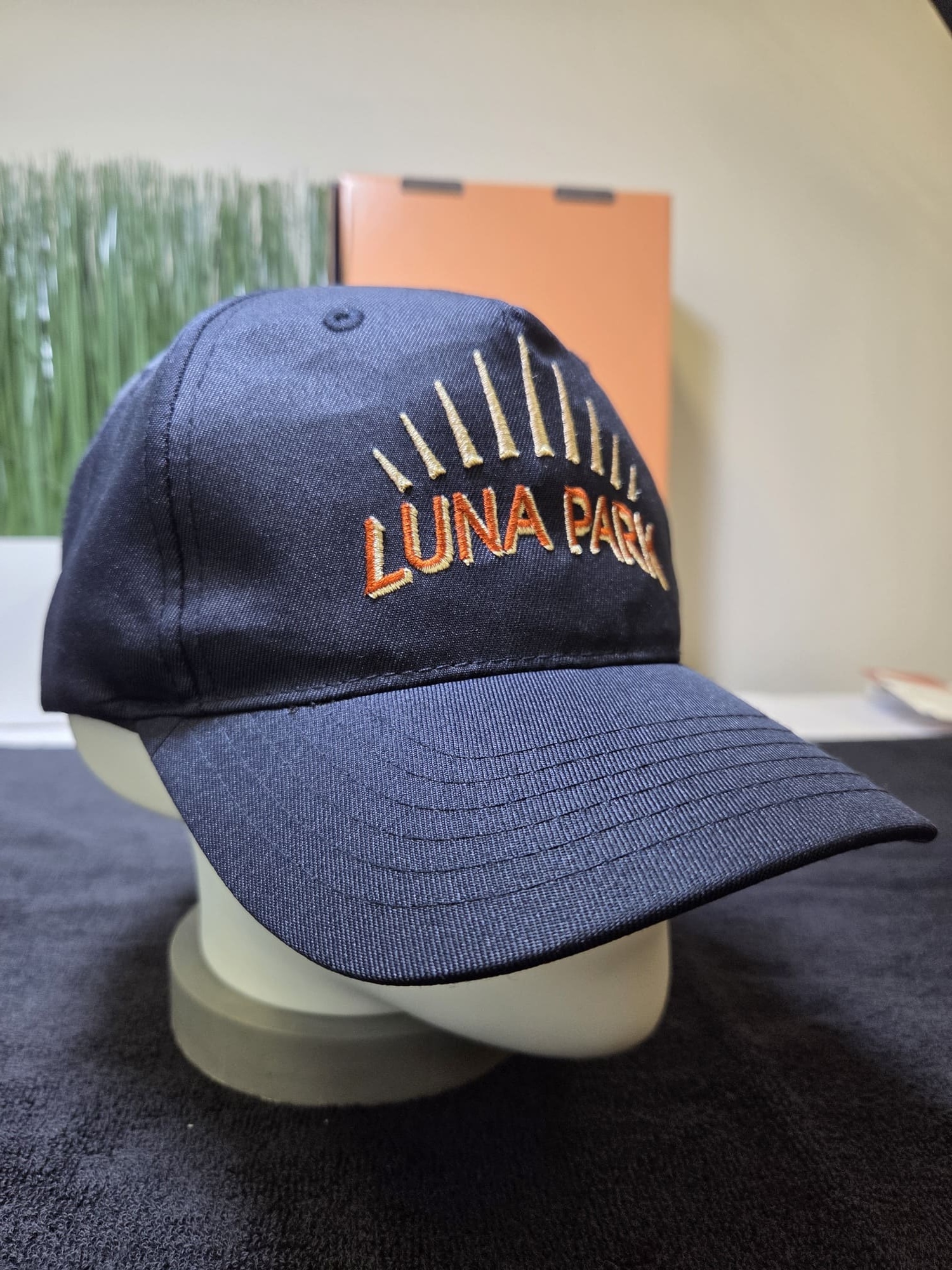 Navy blue Luna Park cap with sun rays embroidered on the front, displayed on a stand.