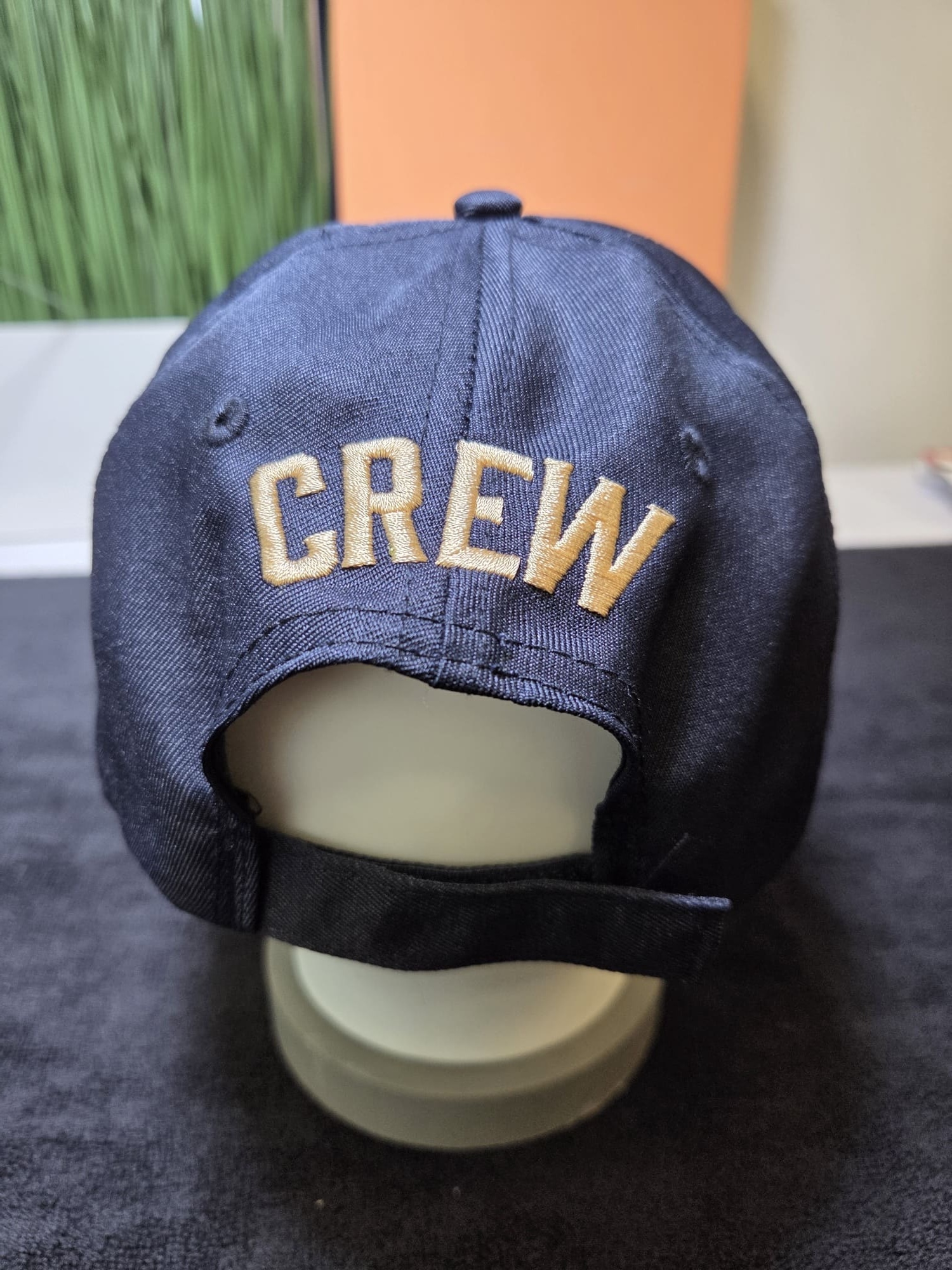 A navy blue Luna Park cap with CREW in beige letters on the back, sitting on a display stand.