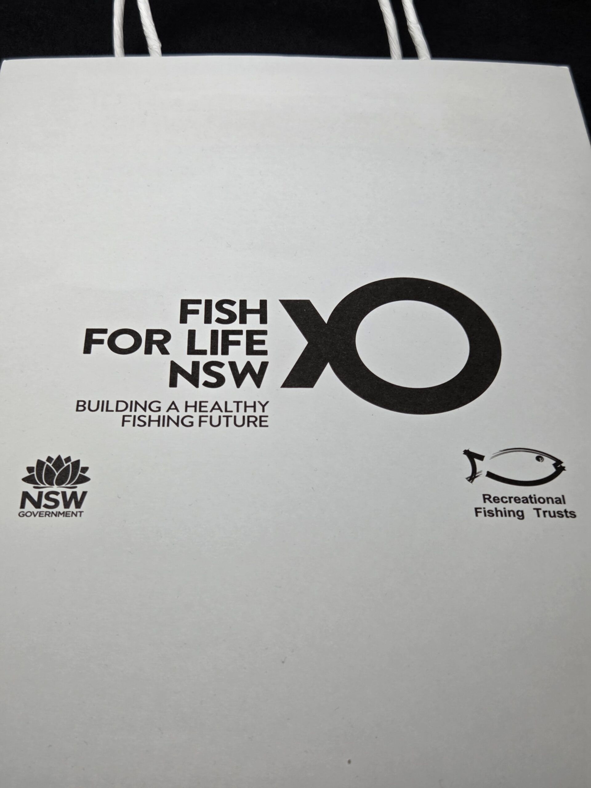 White bag with Fish for Life NSW and NSW Government fishing logos printed in black.