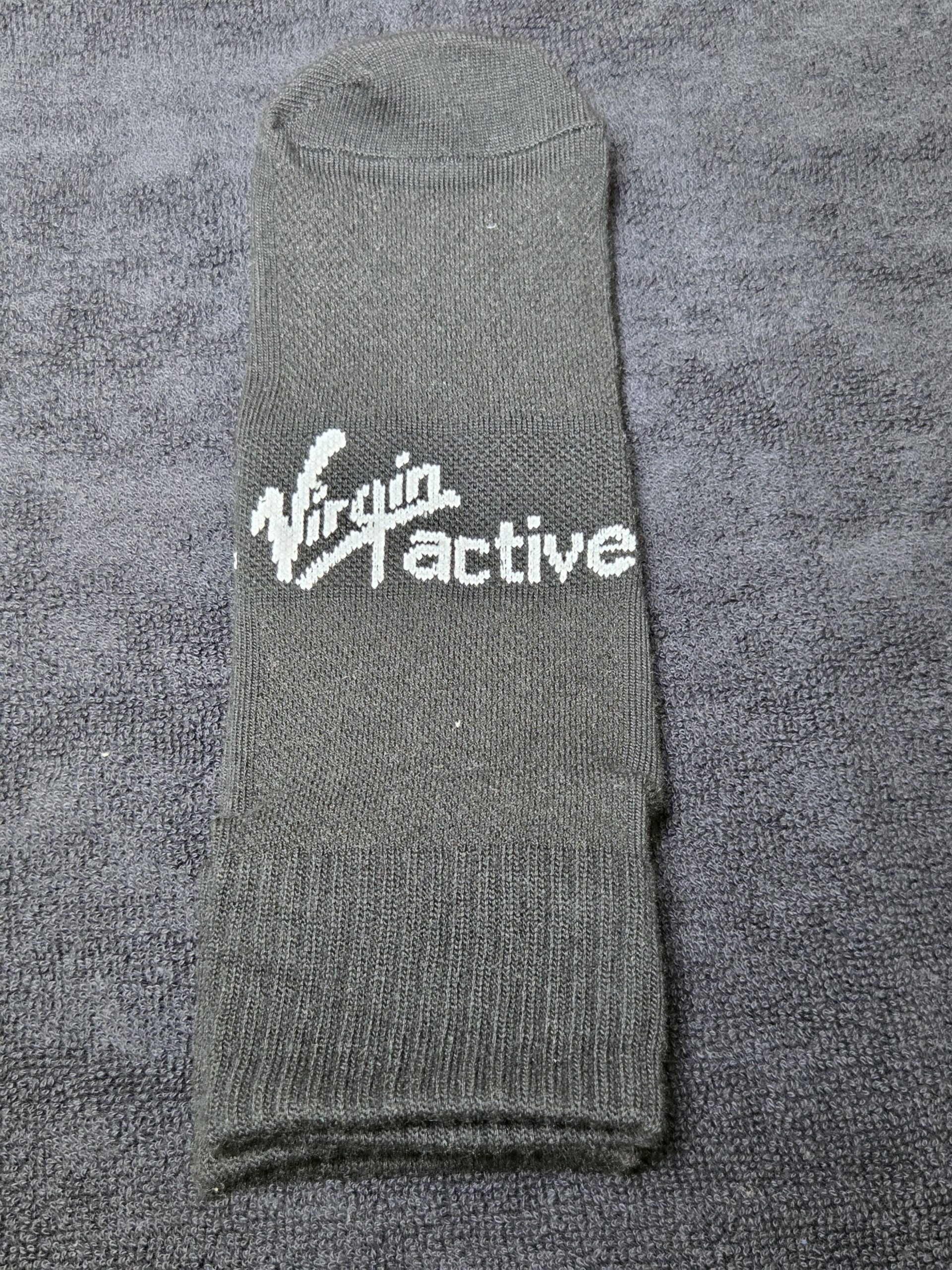 A folded grey gym sock with Virgin Active Australia logo on a grey textured surface.