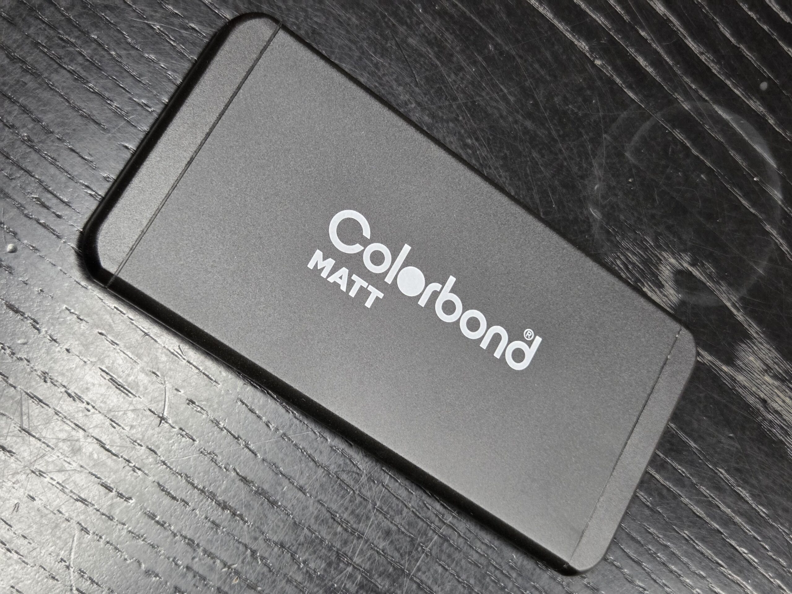 A rectangular COLORBOND Matt sample on a black wooden surface.