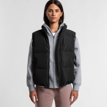 Woman in Uniti Retail black puffer vest, gray hoodie, and pink pants stands facing forward.