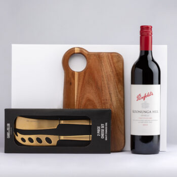 Harcourts wine bottle, wooden cheese board, and knife set on a white background.