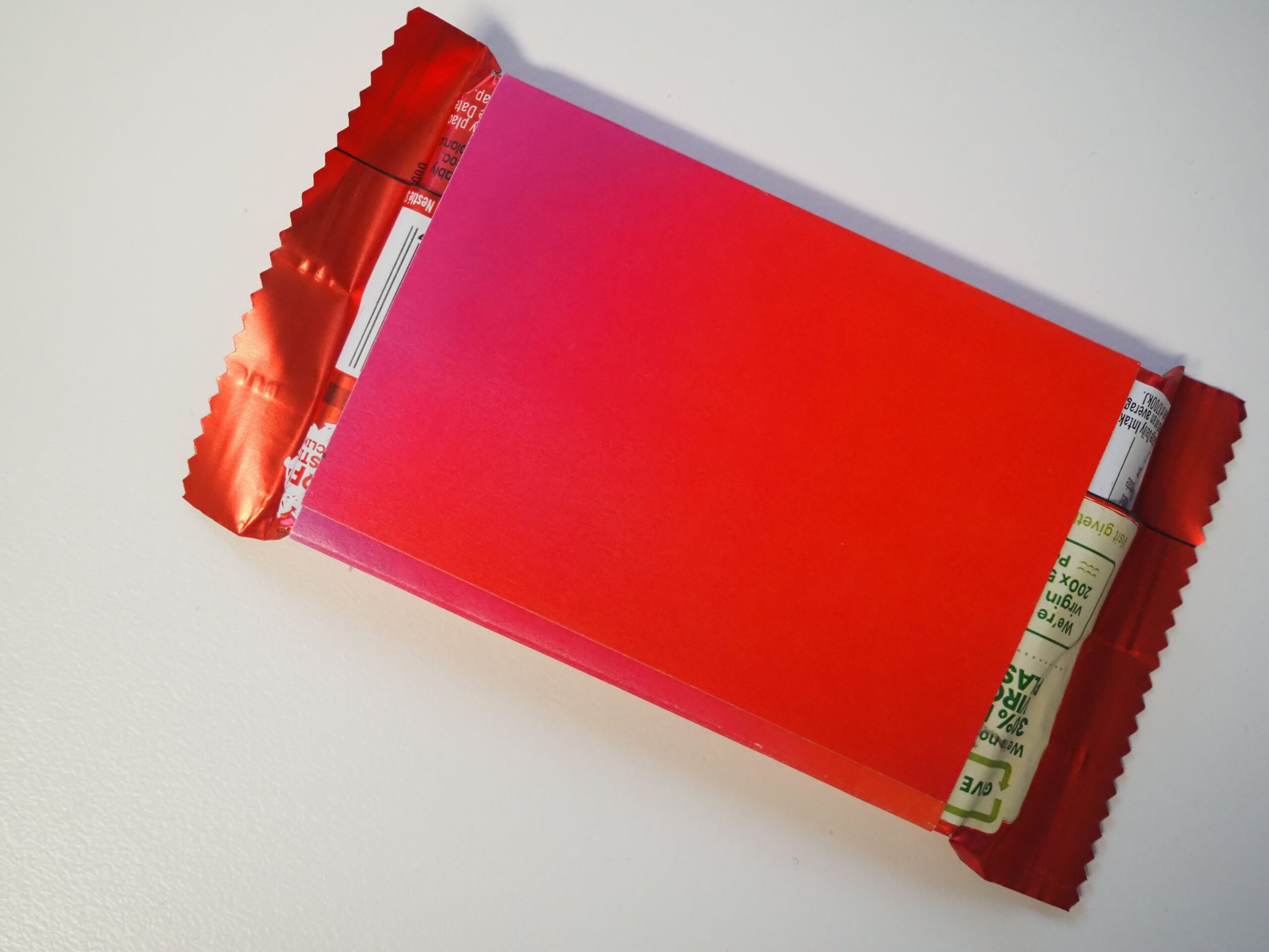 A red-wrapped candy bar, partially opened, revealing a stick of gum inside.