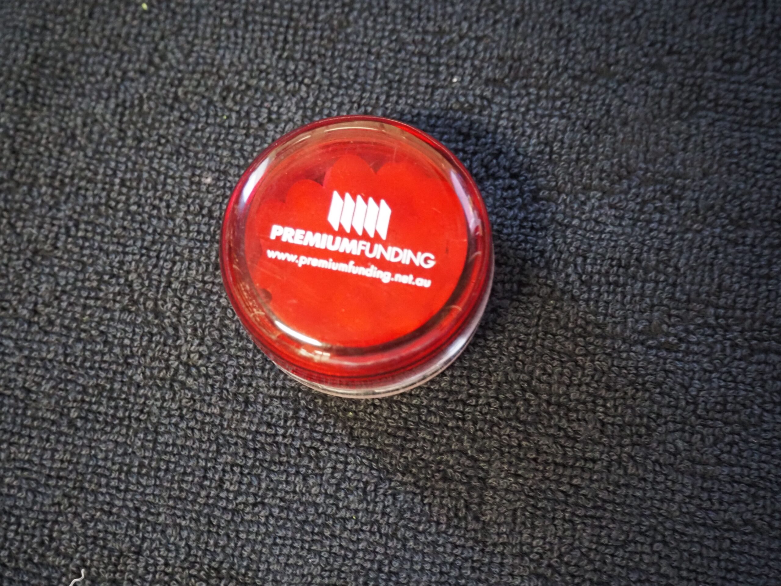 Red container with Premium Funding logo and website, featured in a Client Story on dark fabric.