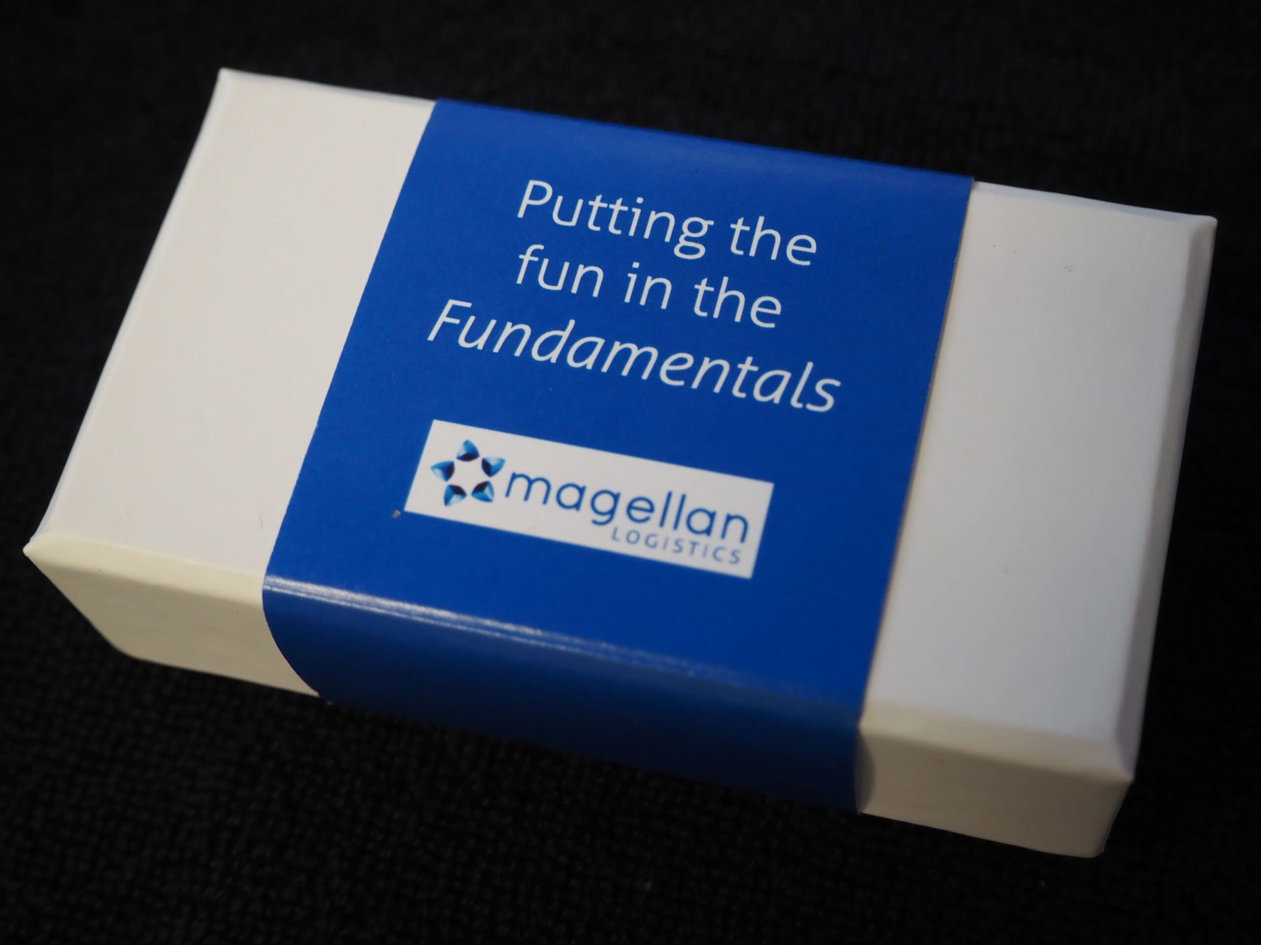 White box with blue label: Putting the fun in the Fundamentals, Magellan Logistics.