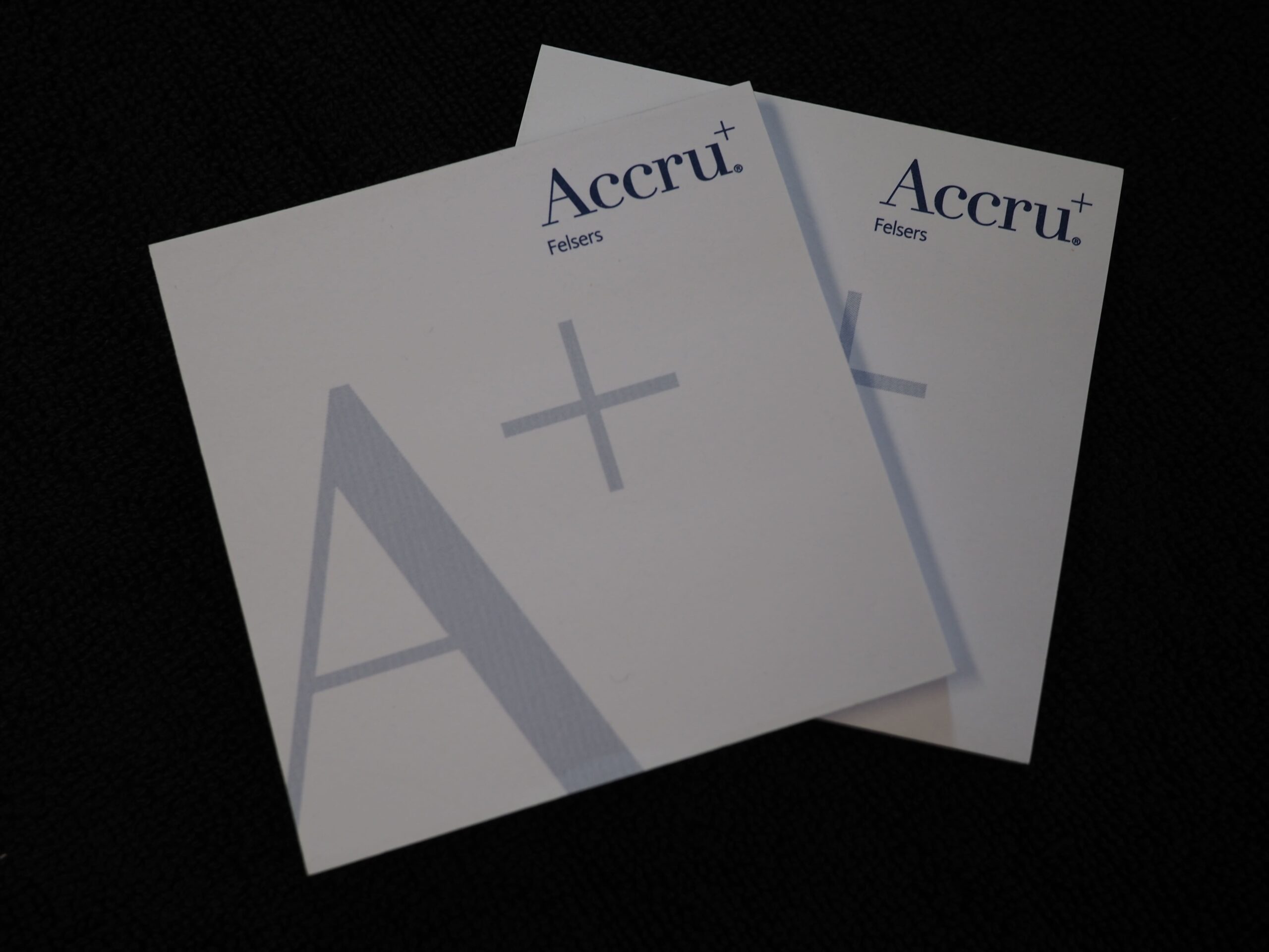 Two white cards with Accru Felsers and a large A+ on a dark background.