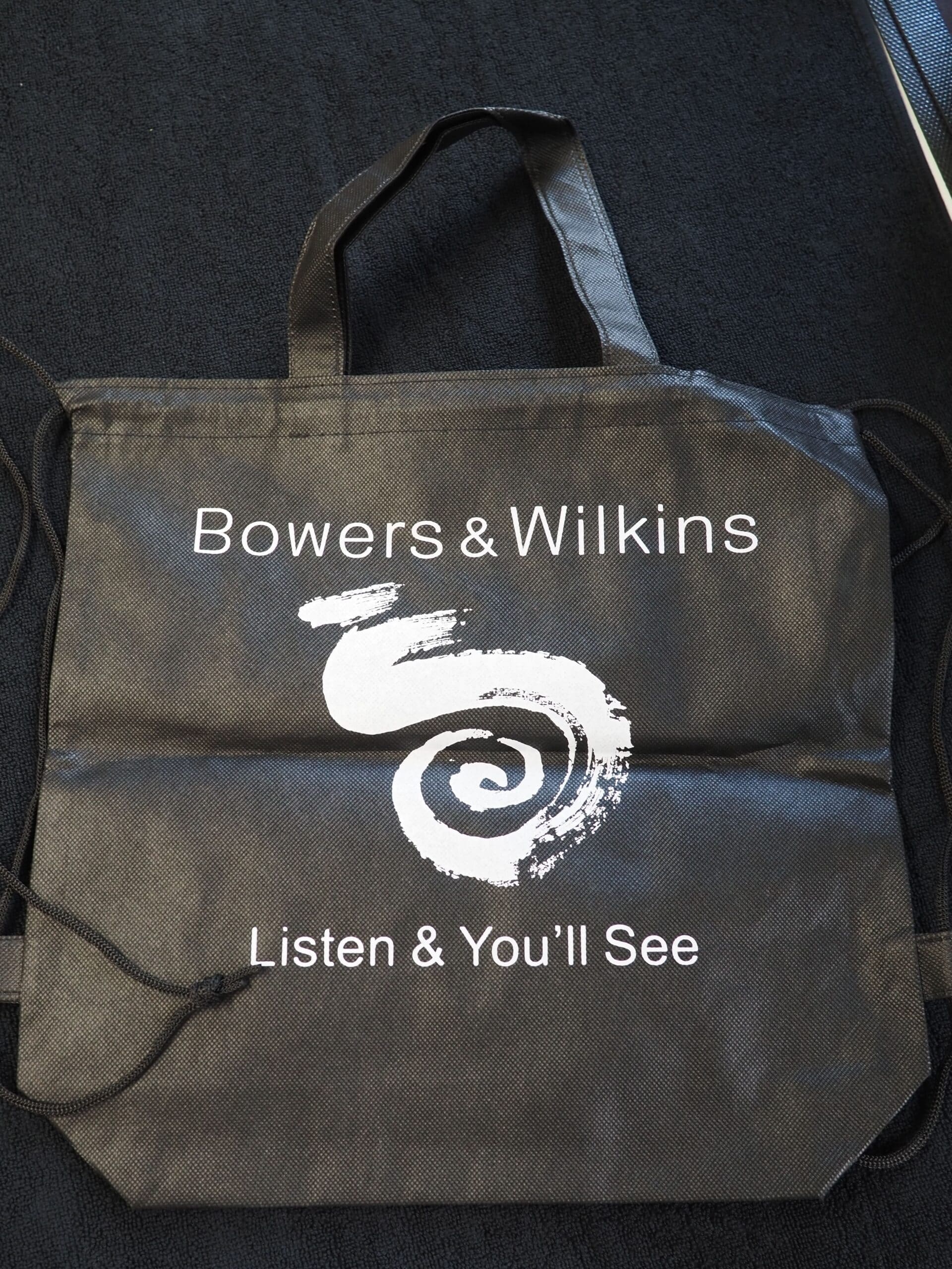 Black Bowers & Wilkins tote bag with Listen & You’ll See and a white spiral logo.