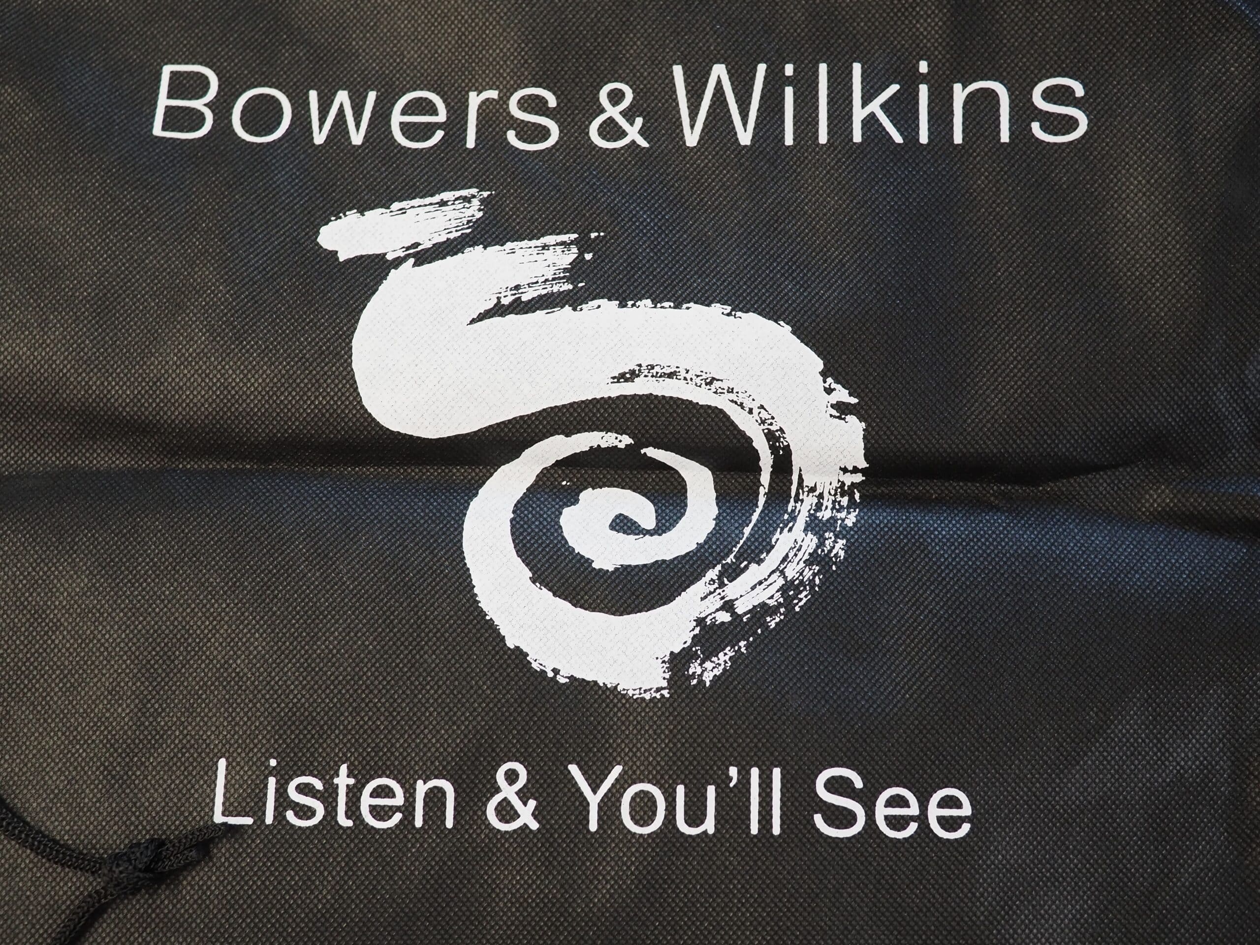 Bowers & Wilkins speakers logo with Listen & You’ll See on a black background.