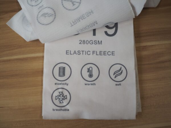 White polo fabric labeled 280GSM Elastic Fleece with icons for elasticity, warmth, and softness.