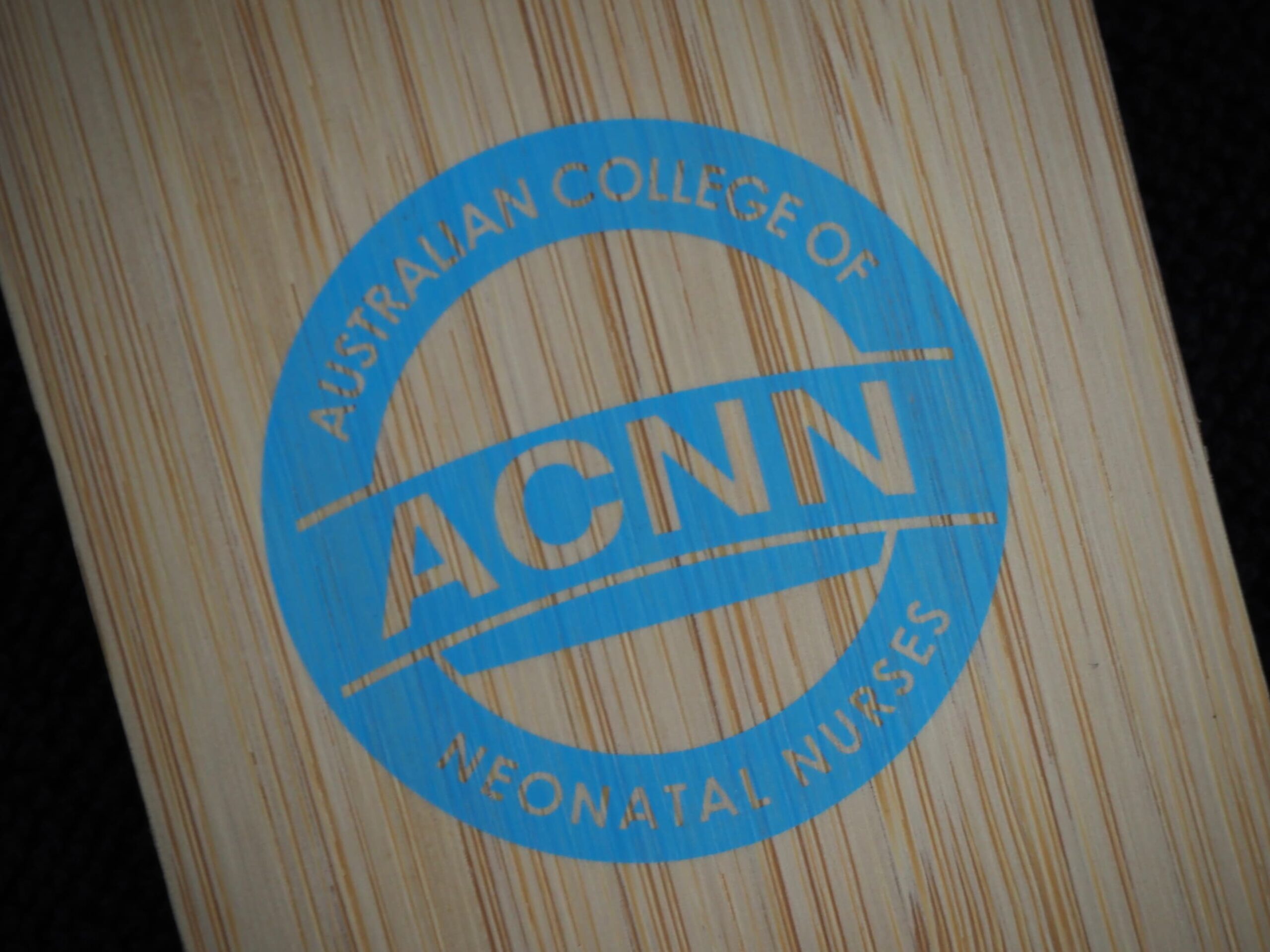 Blue Australian College of Neonatal Nurses logo displayed on a wooden surface in Australia.