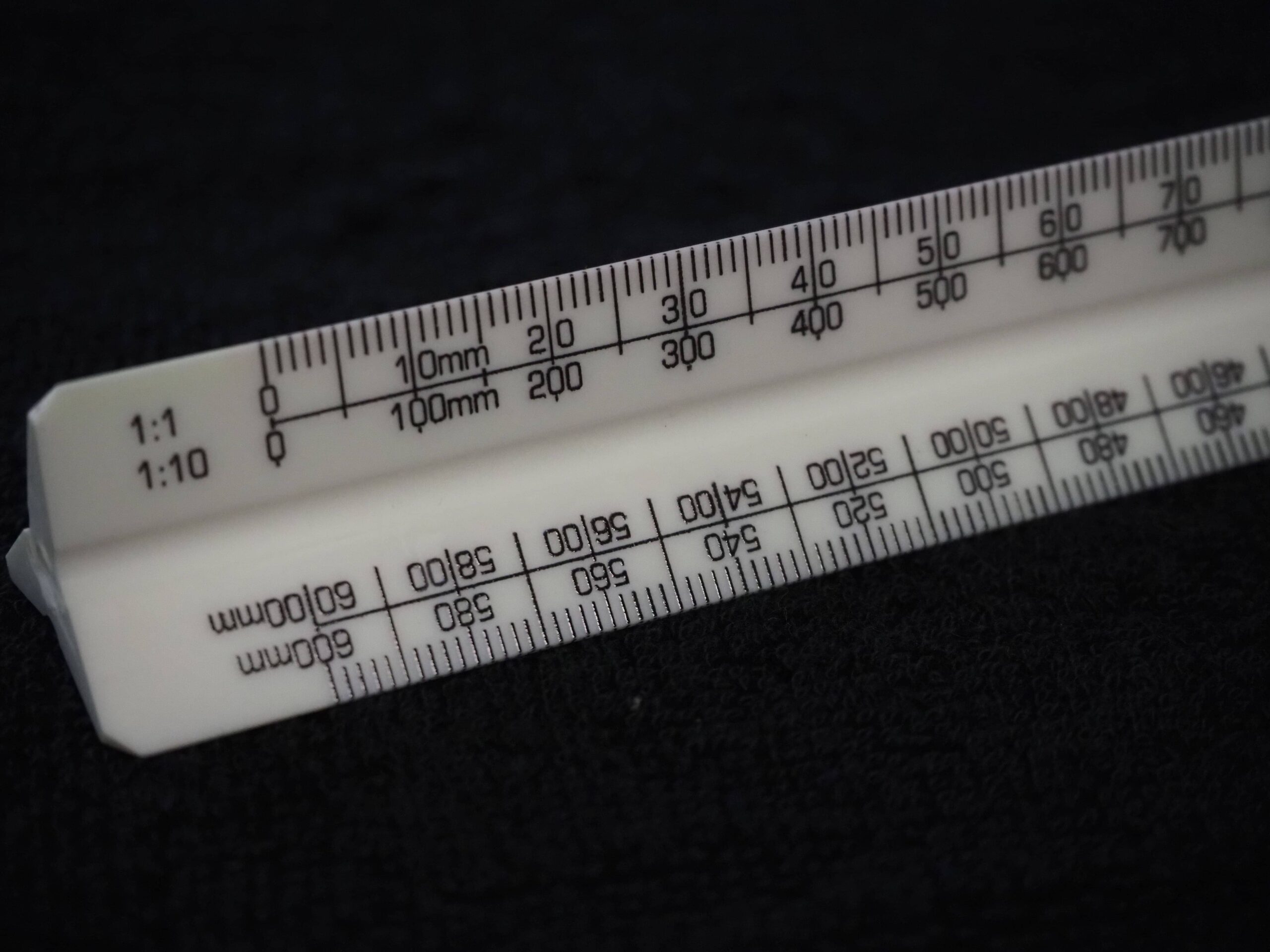 Close-up of a white triangular scale ruler with metric markings, as used in a Bose client story.