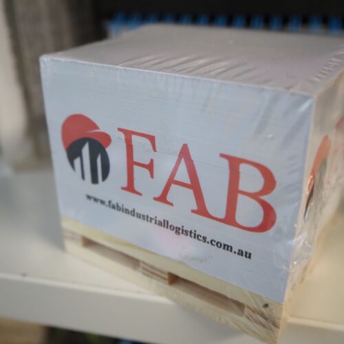 A wrapped box on a shelf labeled FAB—visit fabindustrialogistics.com.au for placing an order.