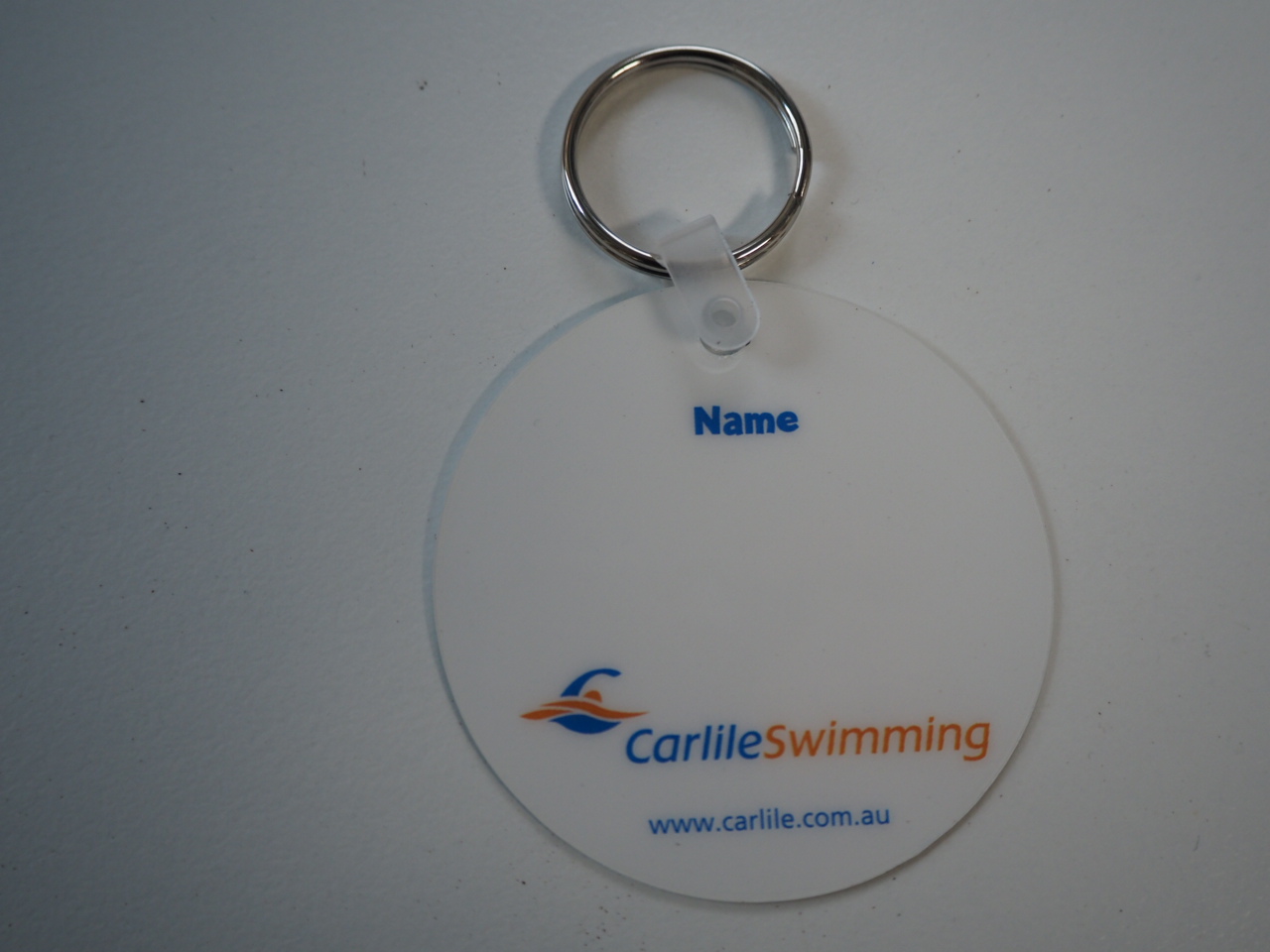 Round Carlile Swimming key tag for swim school with space for a name on a white background.