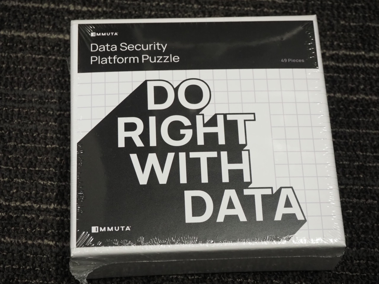 Box labeled Do Right With Data Immuta Data Security Platform Puzzle on a dark carpeted floor.
