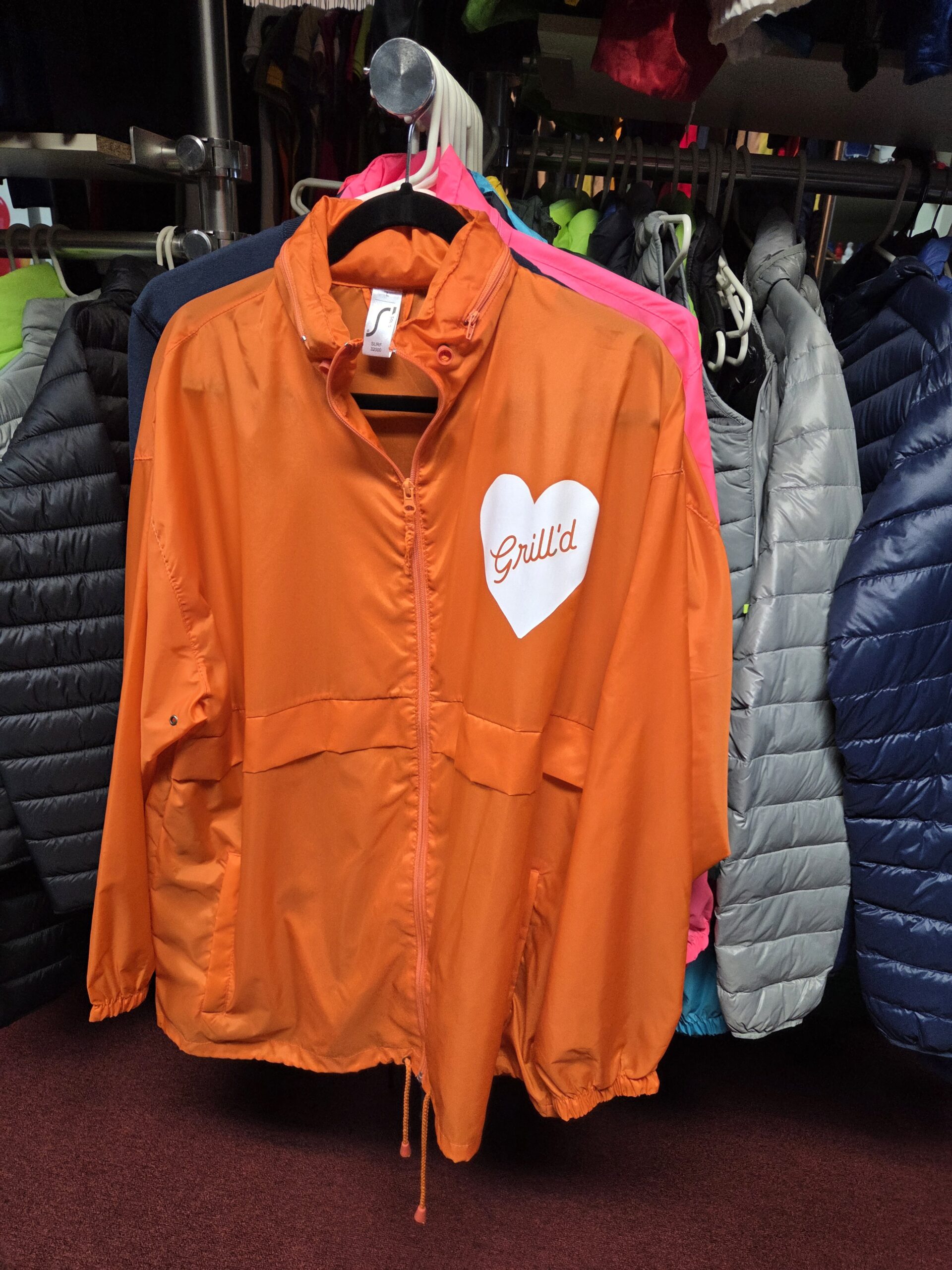 An orange jacket with a white heart and Grilld logo shows why promotional products work.