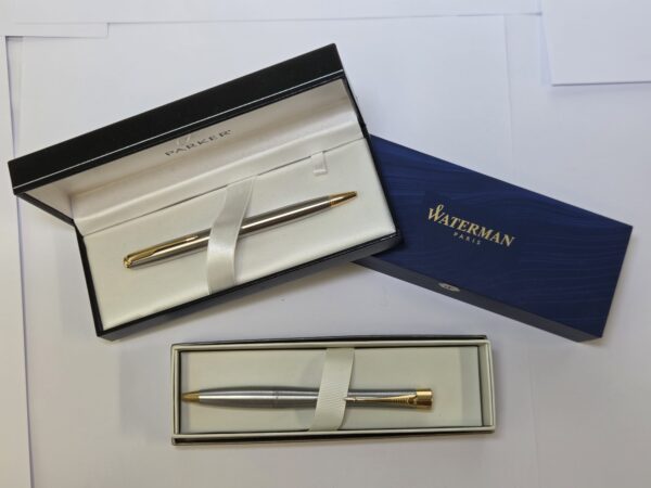 Two luxury pens in open boxes, perfect gifts from Parker and Waterman on a white surface.